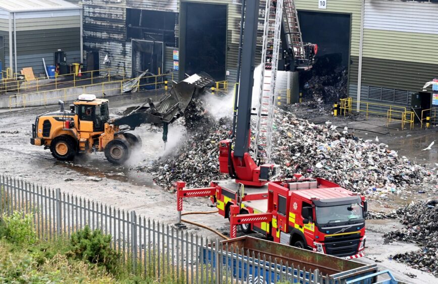  Suez staff working with firefighters to dampen smouldering piles of recycling on day three of the fire at Altens recycling centre.