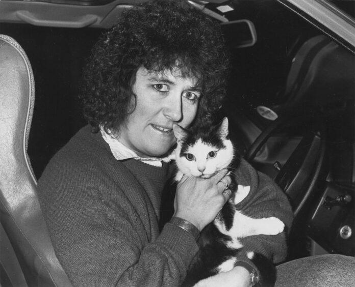 Gail Ross in her car clutching Lucky the cat in her lap. 