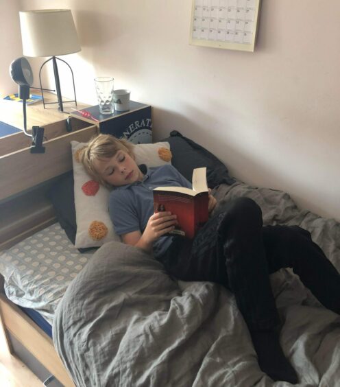 Johan lying in bed reading Harry Potter