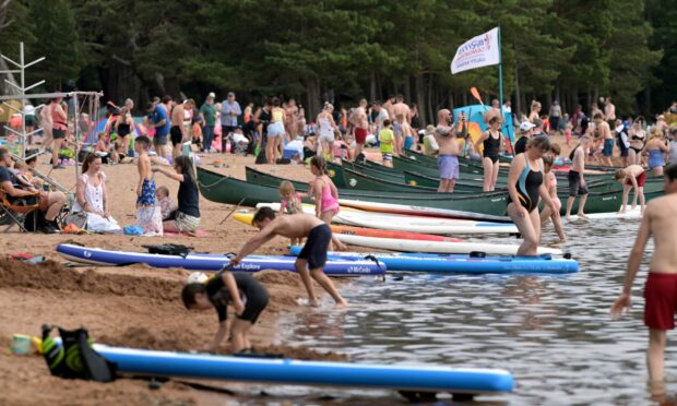 People at Loch Morlich beach during warm weather