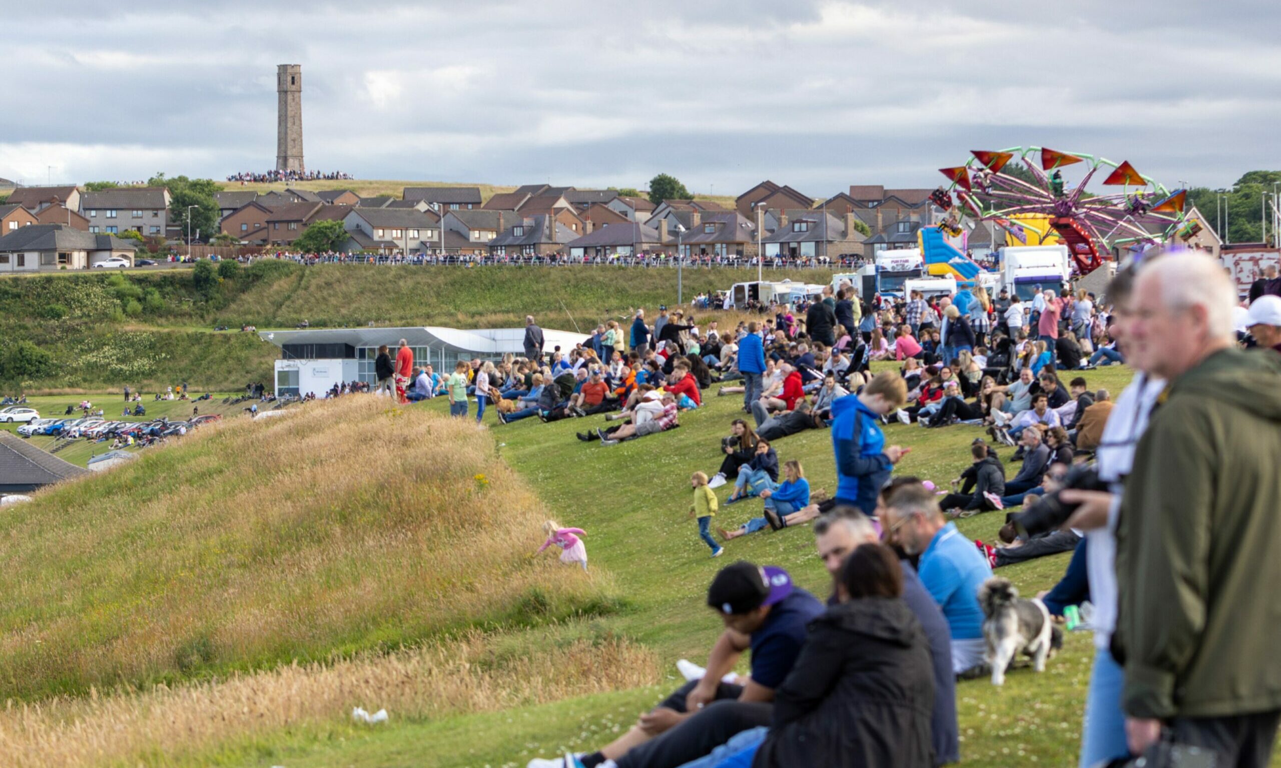 Crowds lined up along a grass bank in Peterhead watching Red Arrows. 