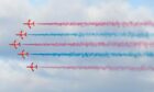 Red Arrows in an arrow formation moving from right to left with blue and red smoke behind.