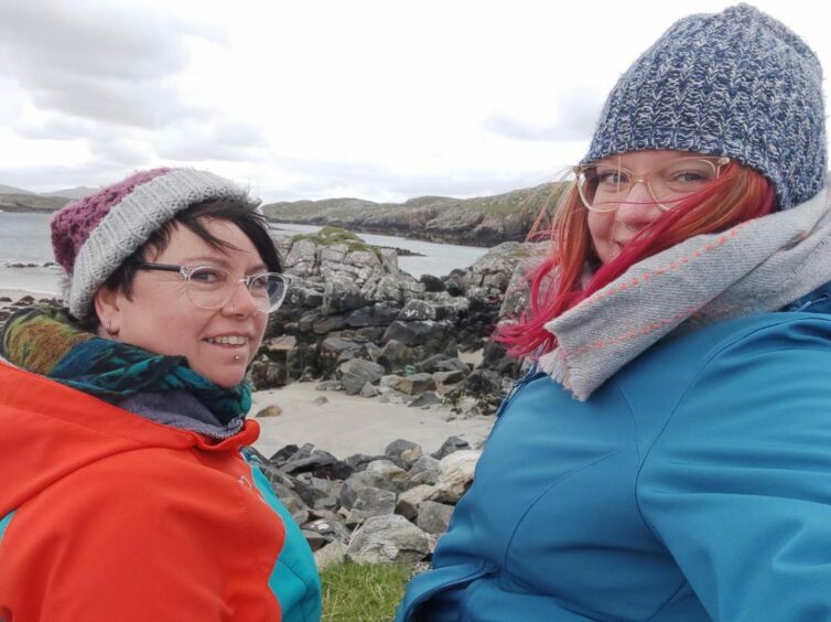 Two women on a beach in Uist, smiling.