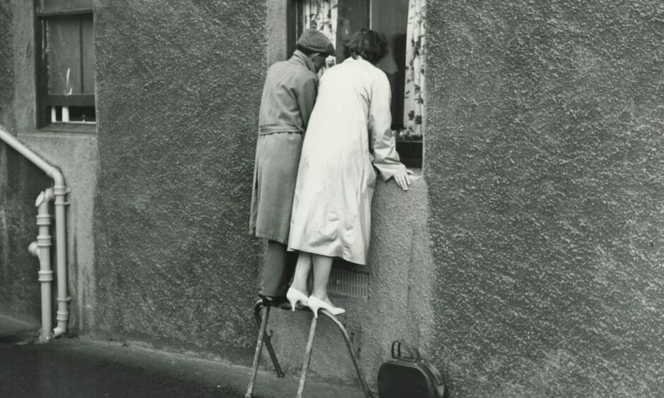 A couple balancing on a rail to reach a hospital window to visit someone during the typhoid outbreak in Aberdeen