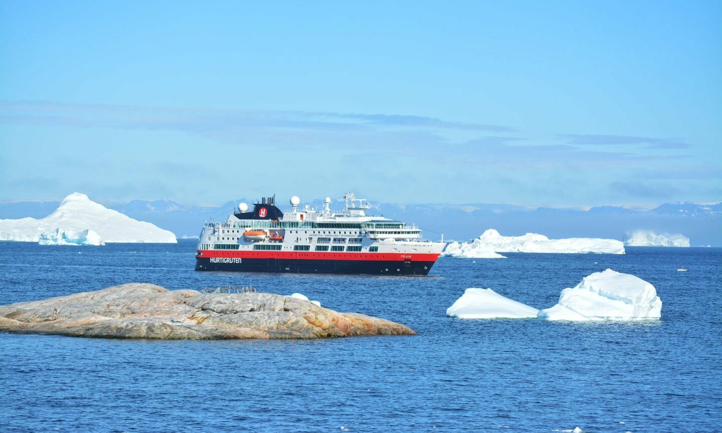 Ilulissat, Greenland - July 4th 2016, Disko Bay Kangia Icefjord, Jakobshavn - huge icebergs in the blue sea on a sunny day, UNESCO world heritage - Hurtigruten ship anchored in the bay