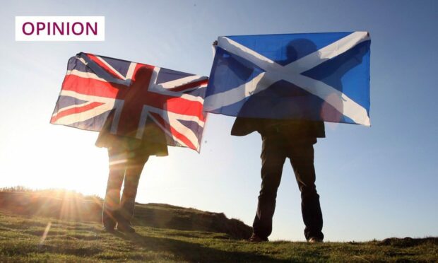 Scottish and English flags held up over Edinburgh, Scotland. Photo:  PA / David Cheskin
