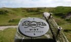 A sign that says 'Uist Unearthed' looking out over an archaeological site.