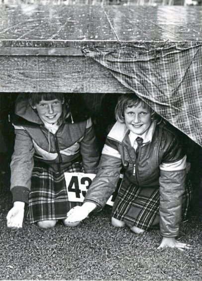 Two young highland dancers sat under the stage to shelter from the rain at the Ballater Highland Games