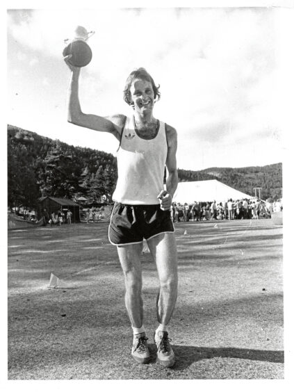 A man holding the silver Jubilee Cup after winning the hill race