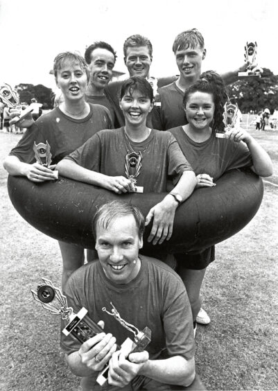 A group of people holding small trophies surrounded by a large inflatable ring at It's a Knockout