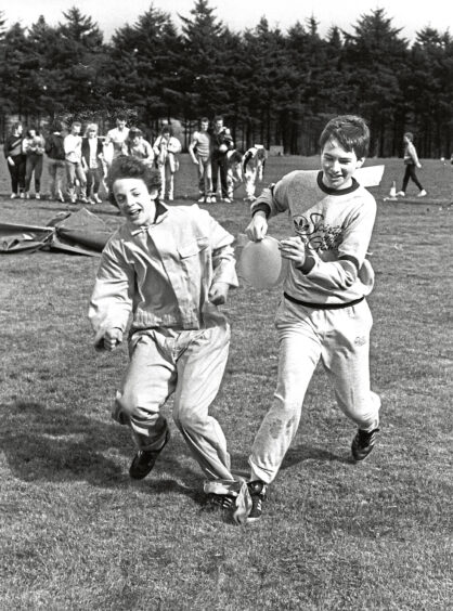 Two young boys running in a three-legged race at It's a Knockout