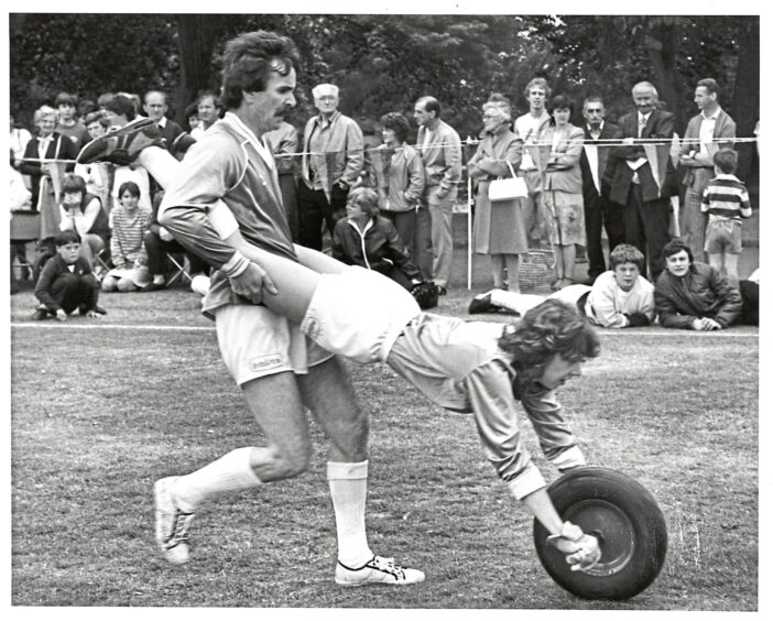 A man and woman in a wheel barrow race at It's a Knockout