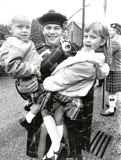 A man in tradition plaid with his young son and daughter