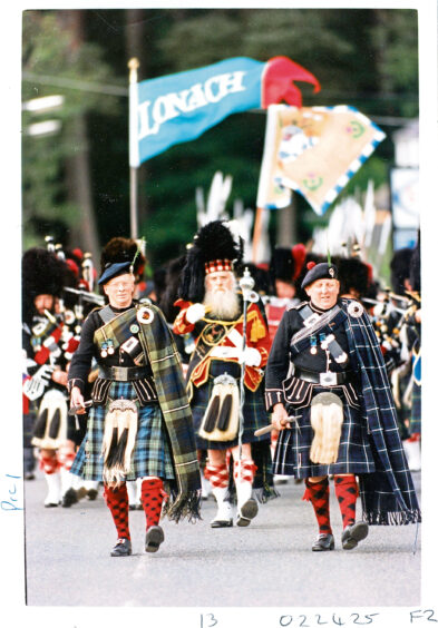 Men of Lonach marching in kilts and traditional clothing.