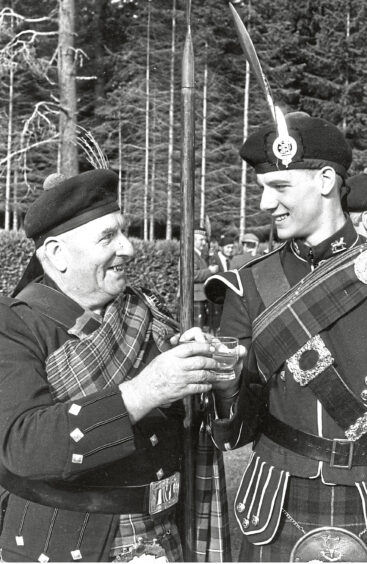An older man and a young man sharing a drink at the lonach gathering in 1990