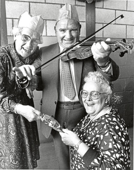 1988 - President of Tillydrone Senior Citizens Club, Cecil Brown tunes into the festive spirit along with club secretary Mabel Mathieson and Gladys Thomson during the club's annual Christmas dinnerdance in the Tillydrone Community Centre