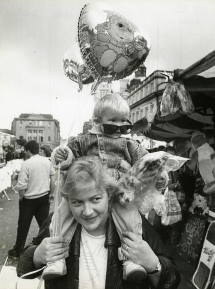1988 - Andres Soto, 2, Aberdeen, hangs on to the goodies while his aunt Miss Linda Munro, Aberdeen, does the carrying at the Aberdeen Timmer Market