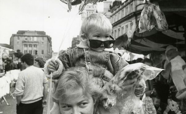 1988 - Andres Soto, 2, Aberdeen, hangs on to the goodies while his aunt Linda Munro, Aberdeen, does the carrying at the Aberdeen Timmer Market