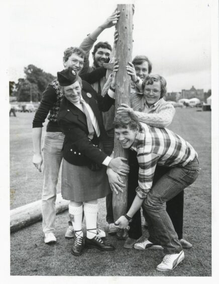 Games committee member Edward Ross shows lads from Dortmund, West Germany, how to handle the caber at Aboyne Games today