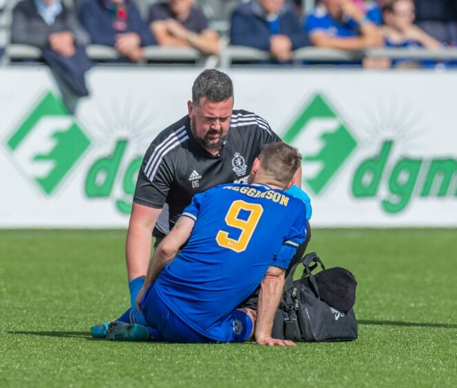 Mitch Megginson is treated by Cove Rangers head physio Donal Gallagher