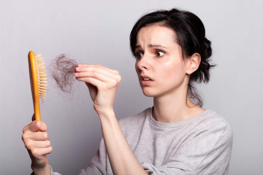 Scared woman pulling large chunk of hair out of her hairbrush