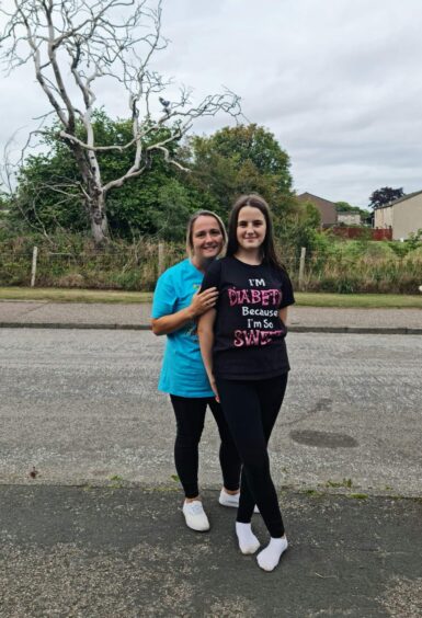 Angela and Lucy Murray standing together by the road and some trees in Laurencekirk