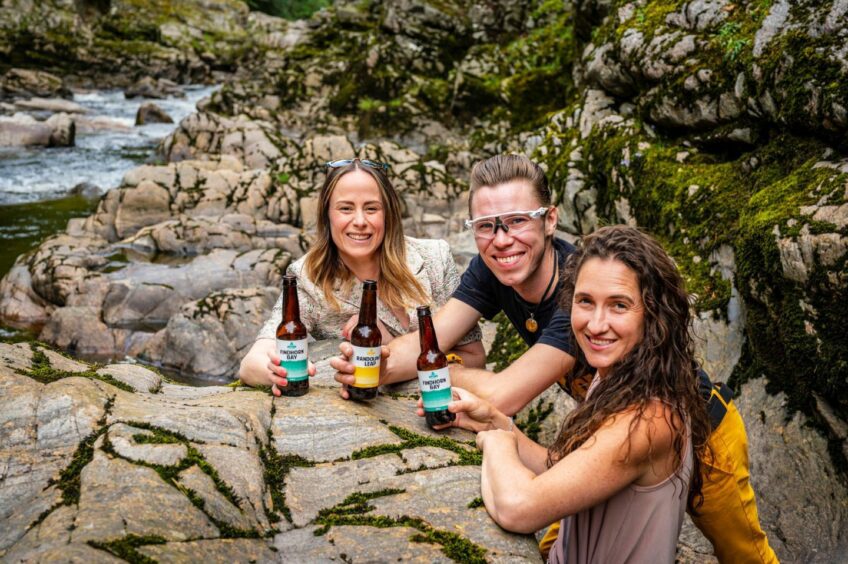 People drinking Speyside Brewery products by river.