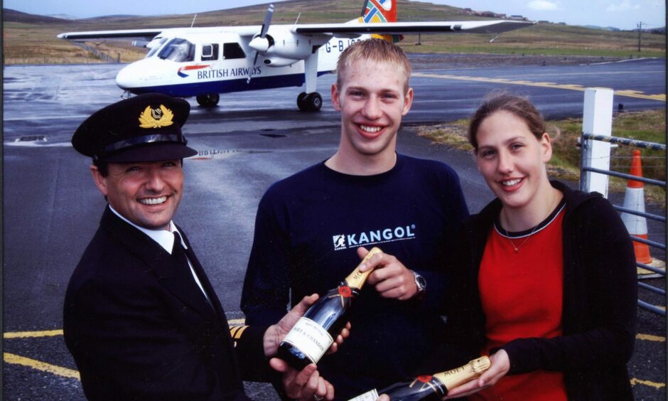 Loganair Captain Eddie Watt presenting twins David and Lynsey Henderson with a gift on their 21st birthday