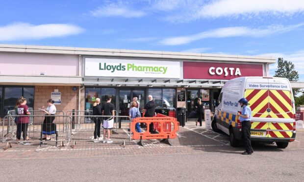 Pictured is the queue and security van outside Lloyds Pharmacy.