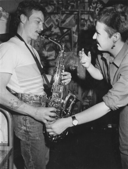 1988 - Alison Souter helps Philip Duthie fix his fingering on the saxophone, urging him to ''make friends'' with the instrument.'