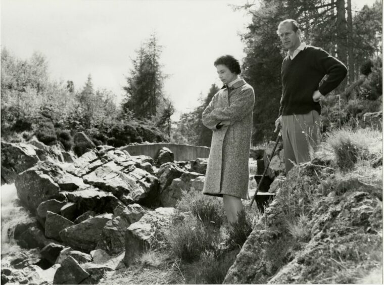 Queen Elizabeth II standing on a banking with Prince Philip on their Silver Wedding anniversary at Balmoral