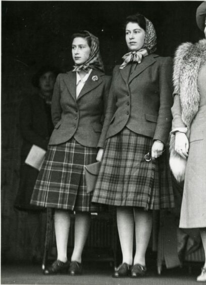 Princess Elizabeth and Princess Margaret standing together in tartan skirts