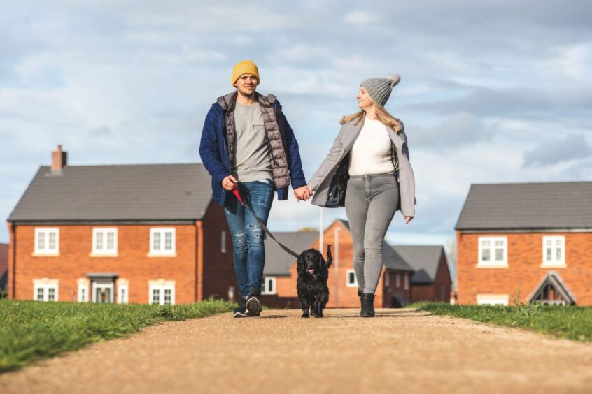 A couple go for a walk with their dog in their neighbourhood