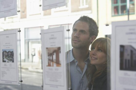 A couple look at properties in an estate agent's window