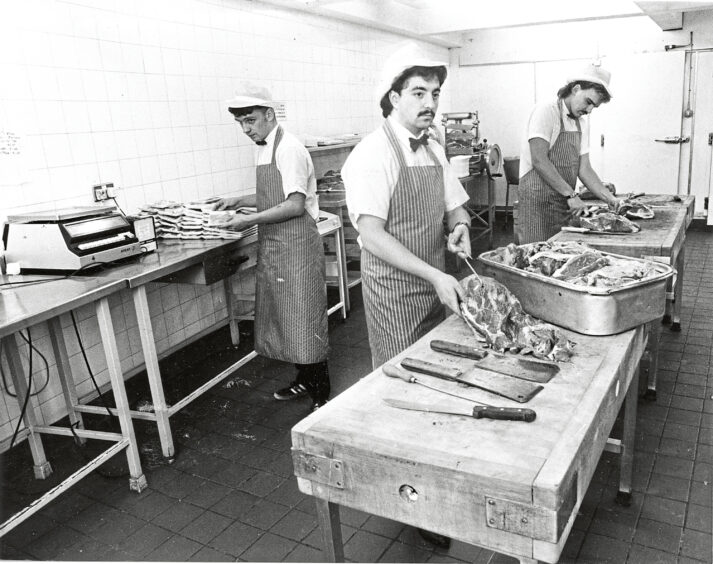 Butcher staff at Littlewoods preparing meat.