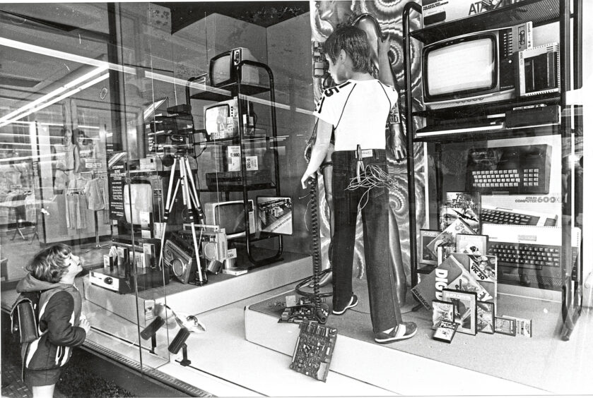 A child in a Littlewoods window display full of televisions and computers.