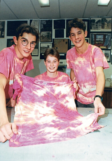 Three students showing off their red and yellow tie-dye t-shirts.