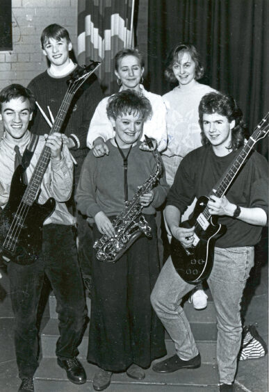 Six teenagers each holding an instrument and smiling at the camera