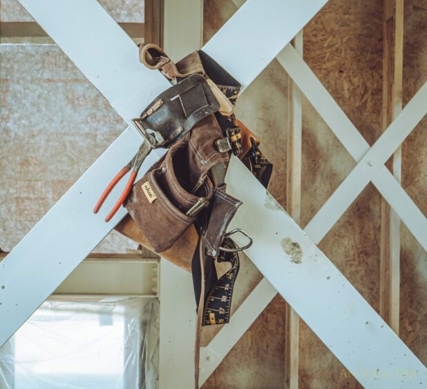 A tool kit hangs on an unfinished wall.
