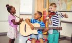 smiling children play instruments as part of their extra-curricular activities in their schools