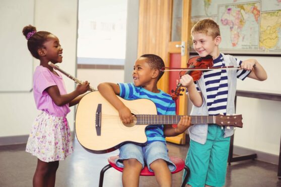 smiling children play instruments as part of their extra-curricular activities in their schools