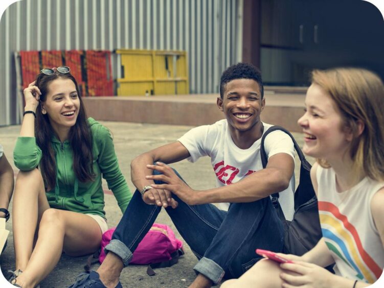 a diverse group of young people sitting around, talking and laughing