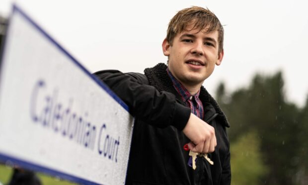 a young man stands beside Caledonian Court, an affordable housing development funded by SSE Renewables' awards