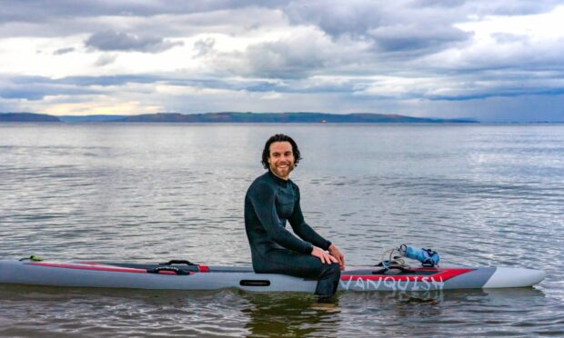 Caorann Fosbrooke sitting on surf board in the middle of the sea