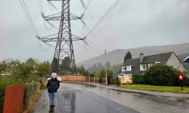 Lisa Beckett of the No More Pylons in Dalmally campaign group beside one of the pylons already situated in the village.