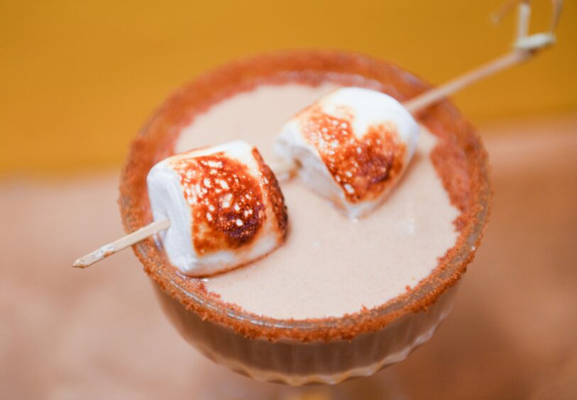 Toasted marshmallows sit atop a Biscoff martini, with a biscoff rim around the glass.