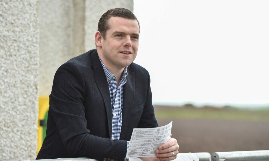 The picture shows Douglas Ross MSP in a suit holding a letter in his hand.