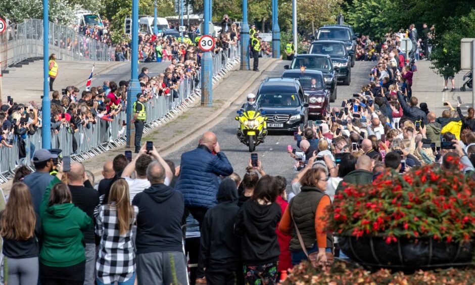 Crowds of people on the streets of Aberdeen watching Queen Elizabeth II's cortege travel through the city.