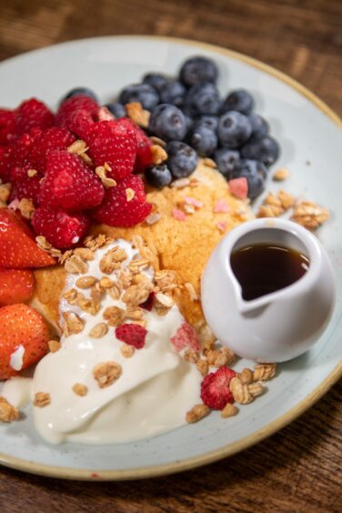 A stack of pancakes with yogurt, oats, raspberries and blueberries