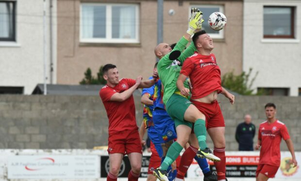 Lossiemouth's Logan Ross, in green, tries to claim the ball against Nairn County